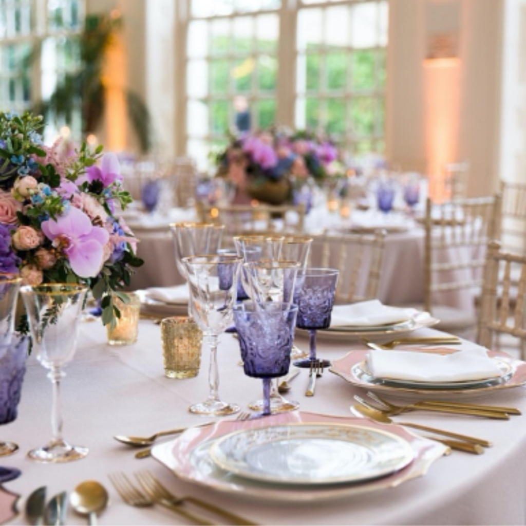 A set table for a wedding, with plates, cutlery, glasses and floral centre pieces.